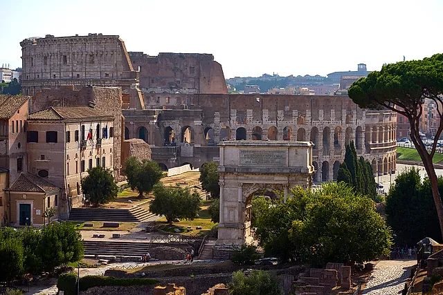 The Colosseum in the distance, behind the Arch of Titus and the umbrella pines