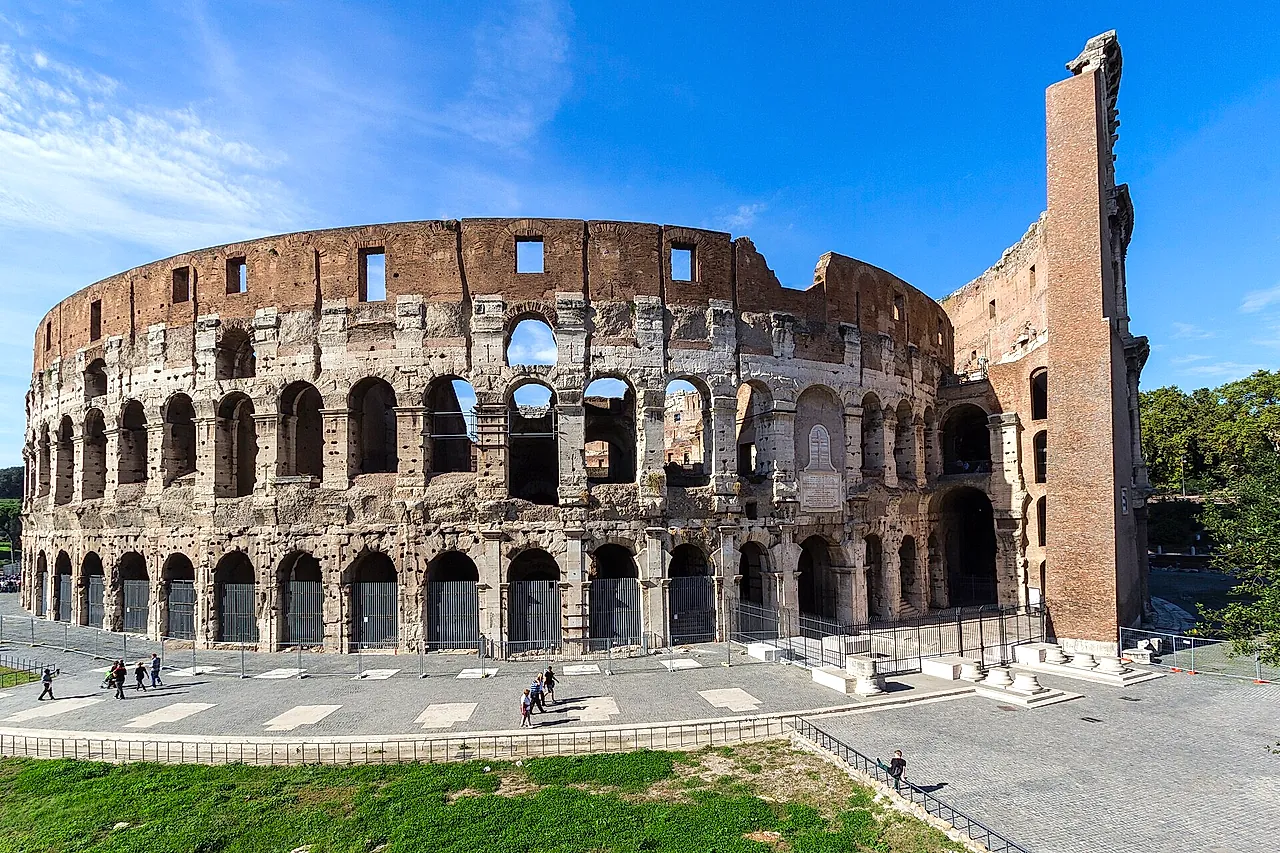 The outer wall of the Colosseum on the east side, with the brick buttress, under a blue sky
