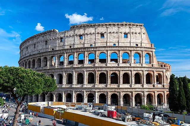 The Colosseum seen from outside on a sunny day, with its three tiers of arches against a blue sky
