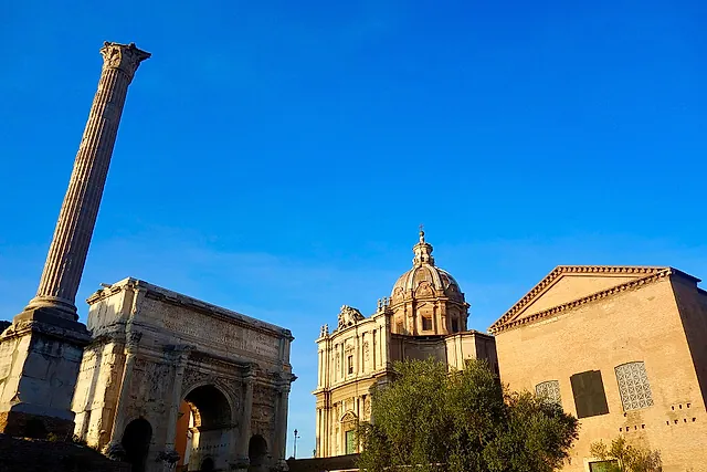 The Column of Phocas, the Arch of Septimius Severus and the Curia in the Roman Forum, under a blue sky